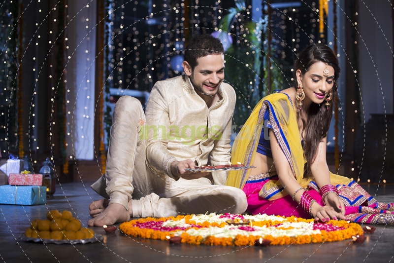 couple sitting and making rangoli on diwali