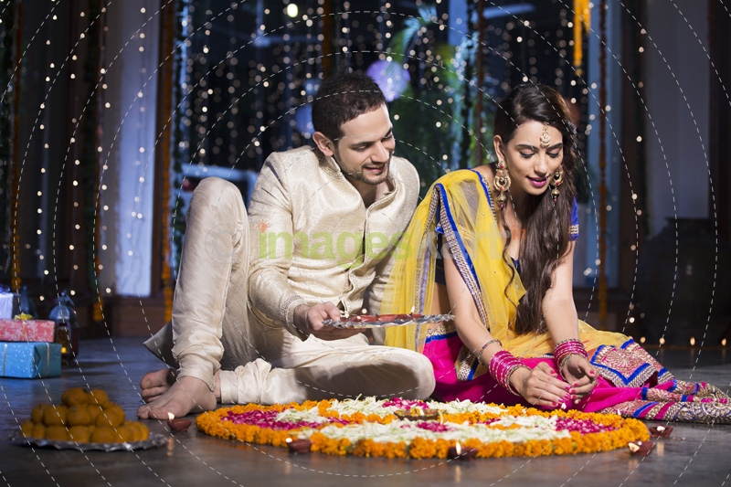 couple sitting and making rangoli on diwali