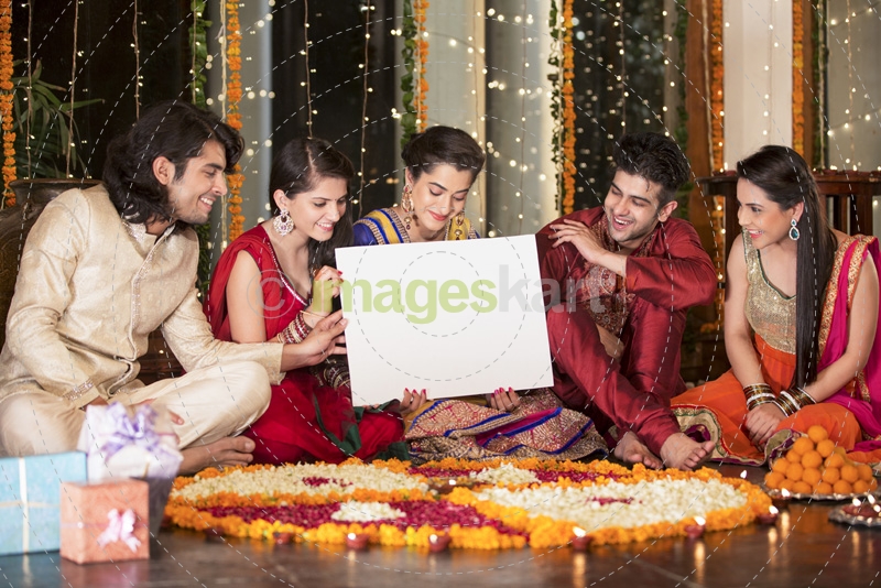 couples in traditional wear sitting with a message board 