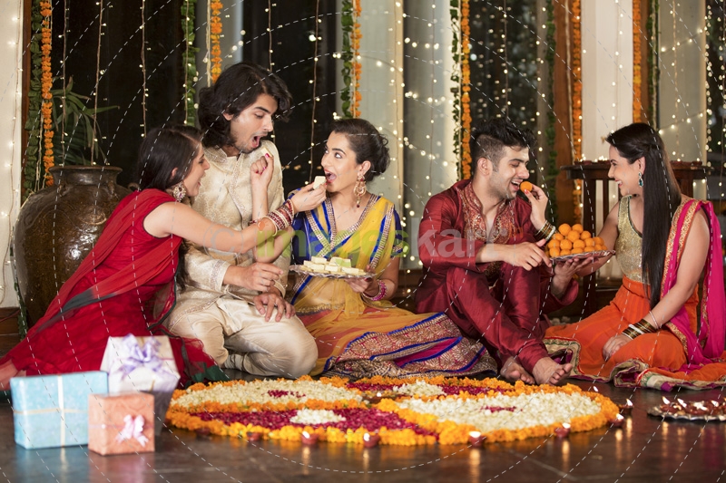 couples celebrating diwali by feeding each other ladoos 