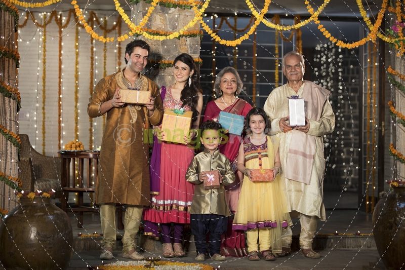 family in traditional wear standing with diwali gifts 