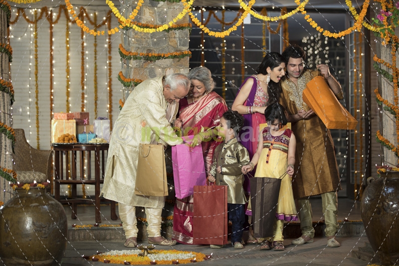 family in traditional wear standing with diwali gifts 