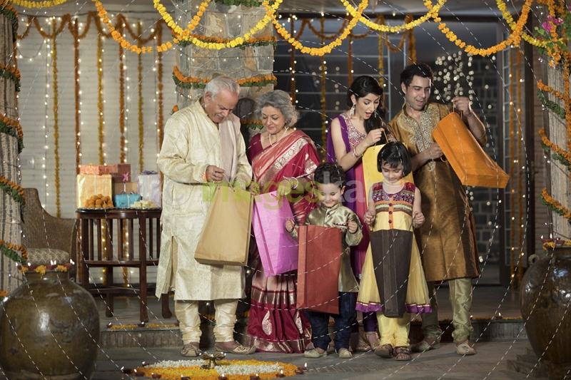 family in traditional wear standing with diwali gifts 