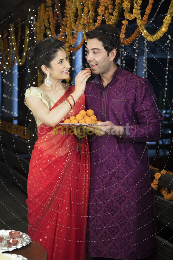 attractive young couple sharing diwali sweets