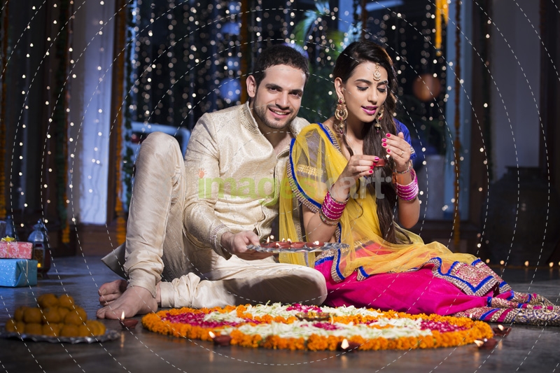 couple sitting and making rangoli on diwali