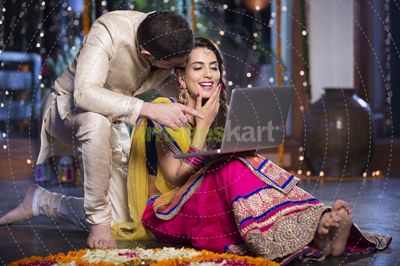 couple in traditional wear sitting with laptop