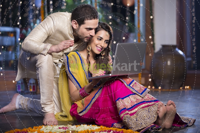 couple in traditional wear sitting with laptop