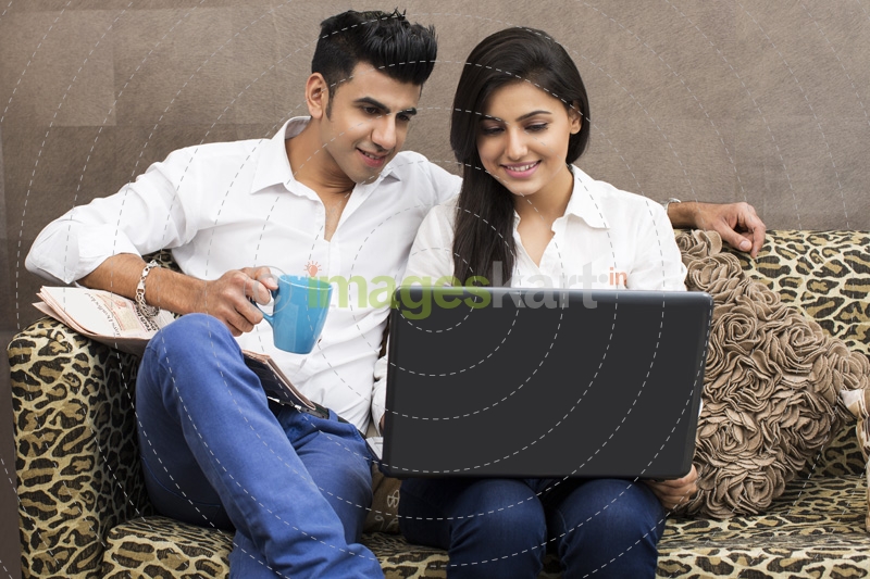 man with coffee looking at woman browsing in laptop