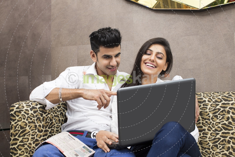 couple on couch browsing in laptop
