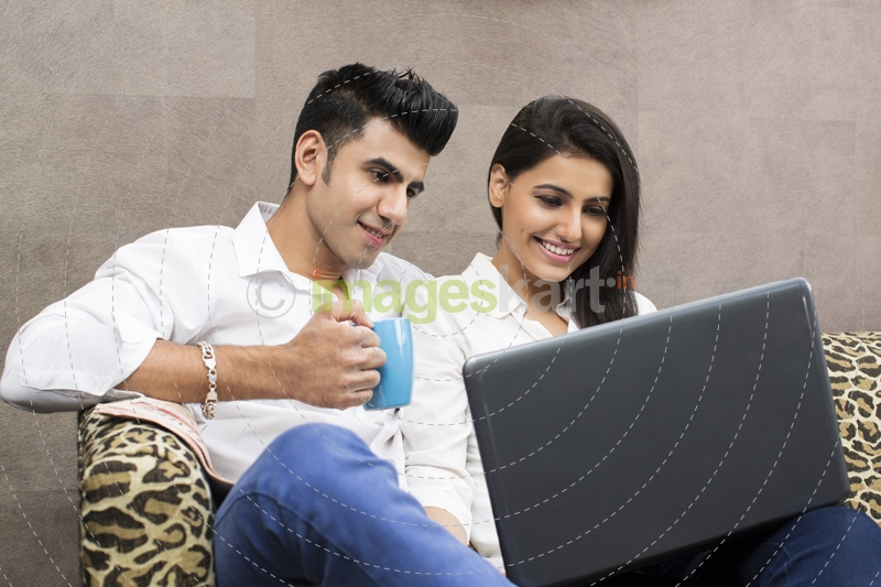 man drinking coffee while woman browsing in laptop