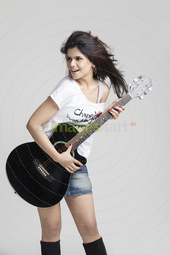 girl wearing short denims posing with a guitar