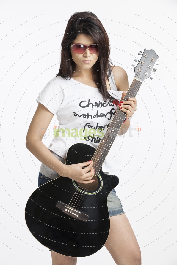 girl wearing short denims posing with a guitar
