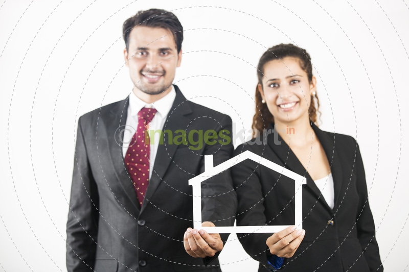 couple dressed as real estate agents holding home frame 