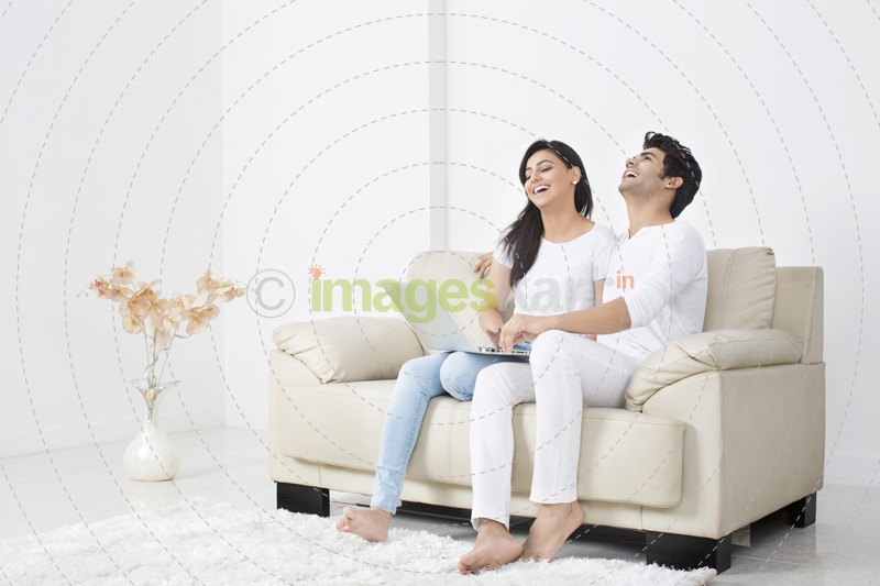 couple on couch having leisure time while browsing in laptop