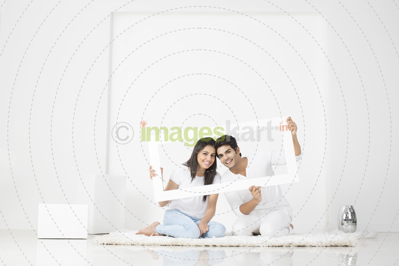 couple posing with frame in new home  