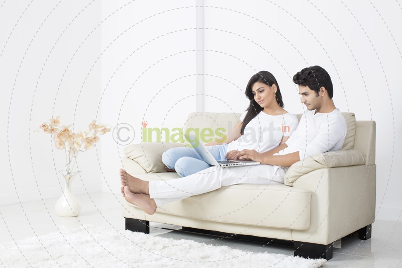 couple browsing in laptop while sitting on couch