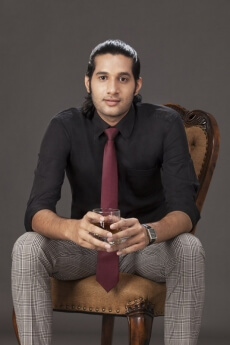 man sitting on chair while holding a drink on grey background 