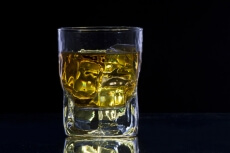 a glass of alcohol with ice cubes