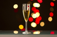 a wine glass on the table with lights in the dark background 