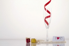 champagne flute with pearls and love note against a white background