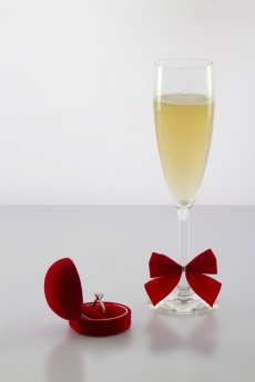 a glass of wine and an engagement ring with white background 