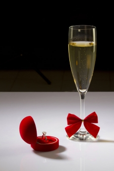 picture of a wine glass and wedding ring on white surface 