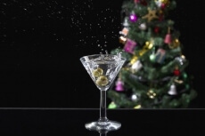a glass full of martini drink with splash from olives