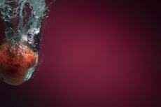apple in water against maroon background 