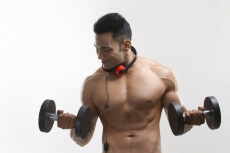 man posing with dumbbells and headphones