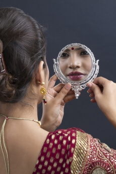 indian bride smiling at reflection in mirror wearing necklace