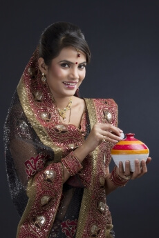 indian woman saving coins in an earthen piggy-bank