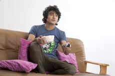 boy on couch operating television remote 
