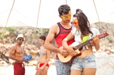couple playing guitar with another couple in the background