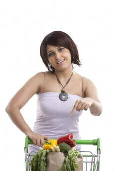 woman pointing towards her vegetables in the cart