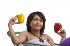 lady holding different coloured capsicums