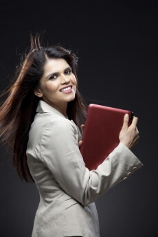 side pose of a corporate lady holding a pink laptop