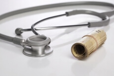 rolled cash with stethoscope on white background
