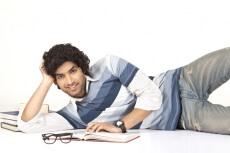 college boy lying around books posing with smile on his face 