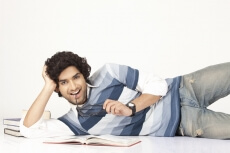 college boy with books around smiling and posing 