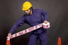 worker blocking the way with caution tape 