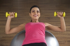 girl at the gym lying over a silver fitness ball