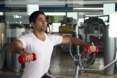 young man lifting light red dumbbells