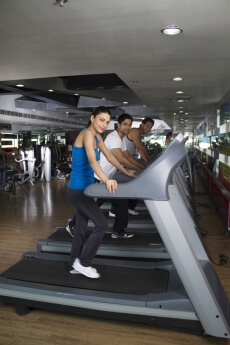 attractive female in blue tank top standing on a treadmill 