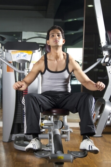 boy sitting and stretching his muscles at the gym