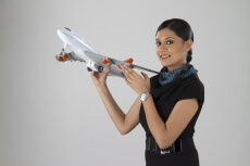 airhostess smiling and posing with an airplane