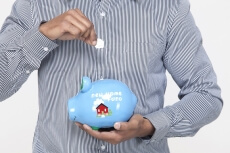 shot of a man dropping a coin in a piggy bank