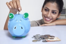 woman dropping coins in a piggy bank
