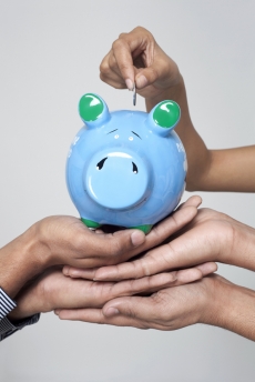 hands putting money in piggy bank