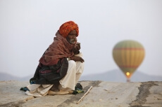 rural man sitting with hot air balloon in background 