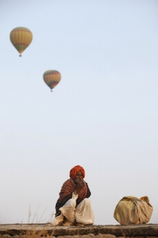 rural man sitting with hot air balloons in background 